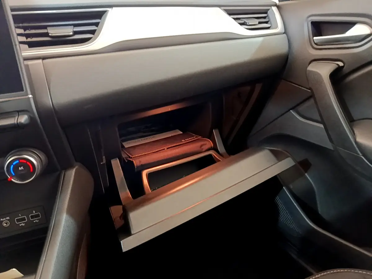 Intérieur du Renault Captur Business 2020, vue côté passager sur la boîte à gants ouverte avec manuel visible.