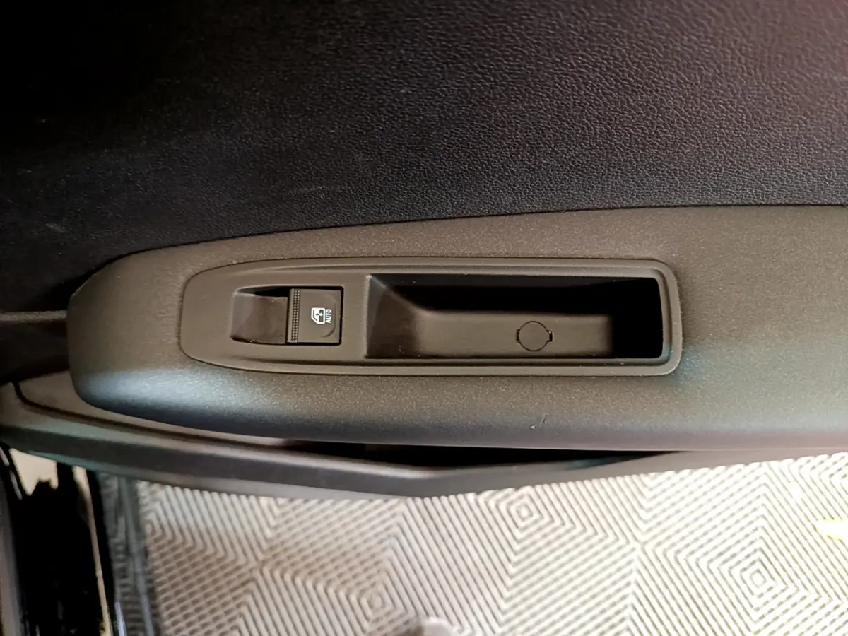 Détail de la commande de lève-vitre côté conducteur sur la porte intérieure noire d'un Renault Captur 2020 Business Blue dCi.