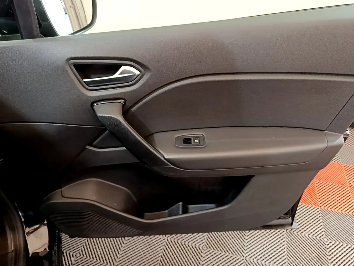 Vue rapprochée de la porte intérieure côté gauche noire du Renault Captur Business Blue dCi 95, avec poignée et commande de vitre.