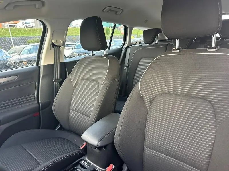 Intérieur de la Ford Focus 2023, vue sur les sièges avant en tissu noir avec accoudoir central et ceintures visibles.