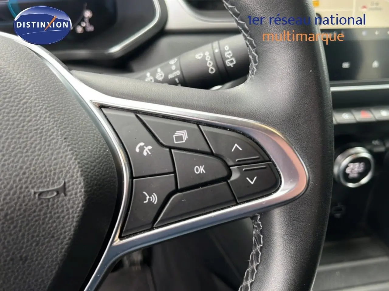 Gros plan sur les commandes au volant à droite du Renault Captur hybride rechargeable, cuir noir avec surpiqûres blanches.