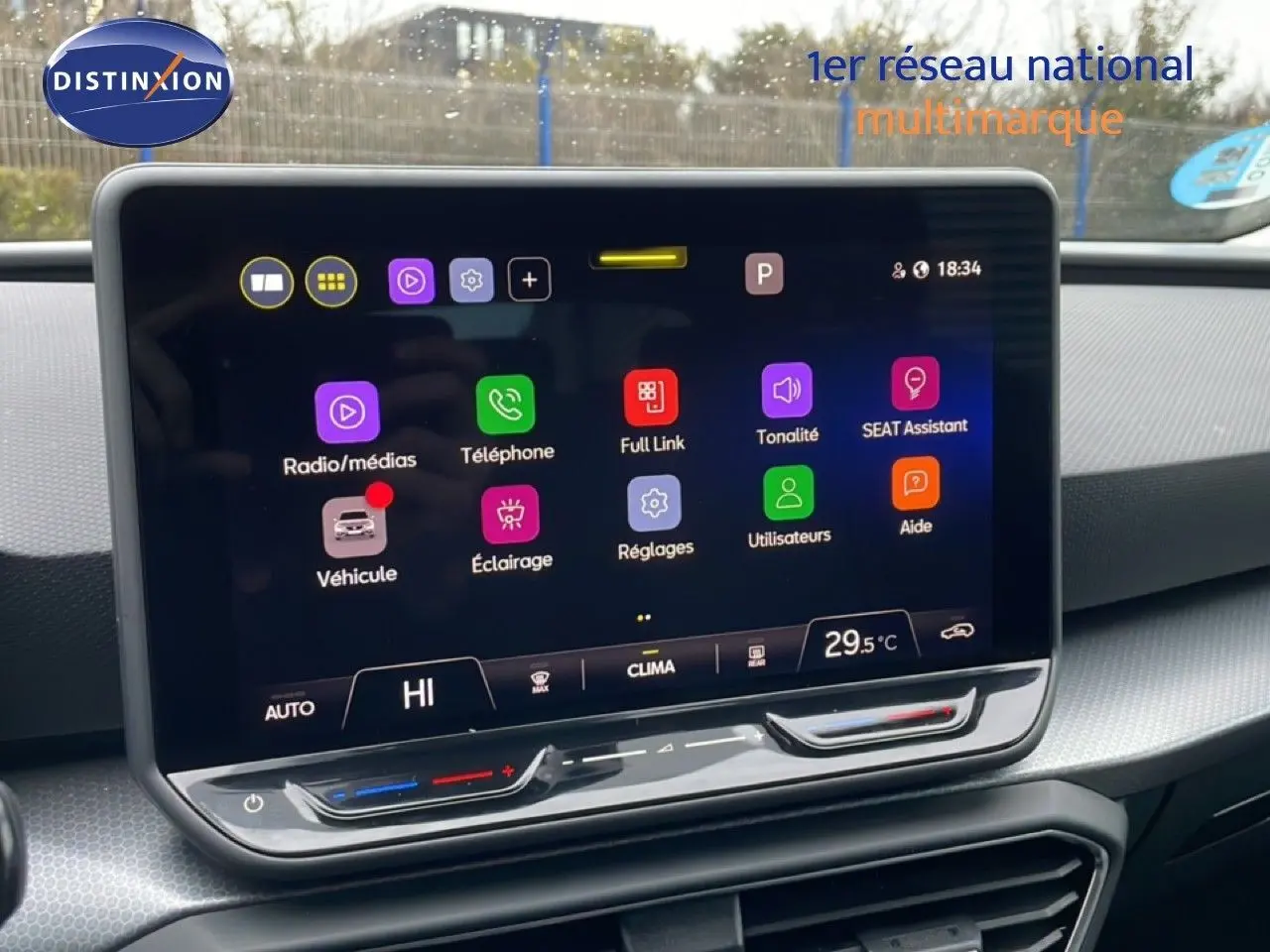 Vue intérieure centrée sur l'écran tactile du tableau de bord du SEAT LEON ST bleu Fjord, affichant les options multimédia et climatisation.