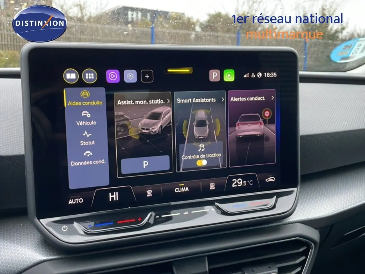 Vue intérieure centrée sur l'écran tactile du tableau de bord du SEAT LEON ST bleu Fjord, affichant les aides à la conduite.
