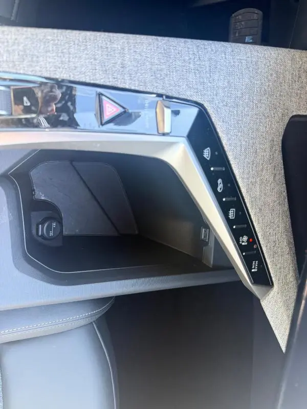 Vue rapprochée de la console centrale grise du Peugeot 3008 Hybrid 145 e-DCS6 Allure avec commandes tactiles et prise 12V.