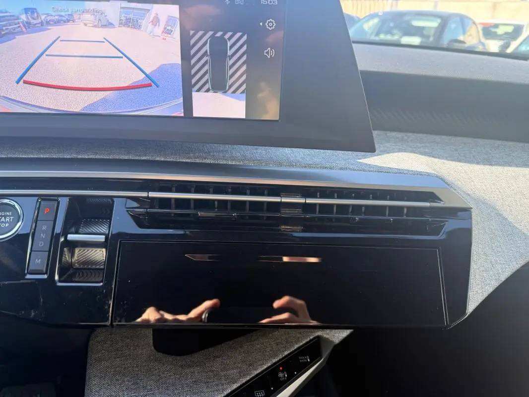 Vue intérieure du tableau de bord du Peugeot 3008 Hybrid gris, avec écran de caméra de recul et commandes modernes.