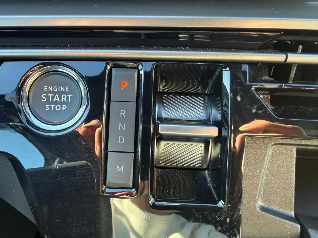 Gros plan sur la console centrale noire brillante du Peugeot 3008 Hybrid avec bouton start/stop et commande de boîte automatique.