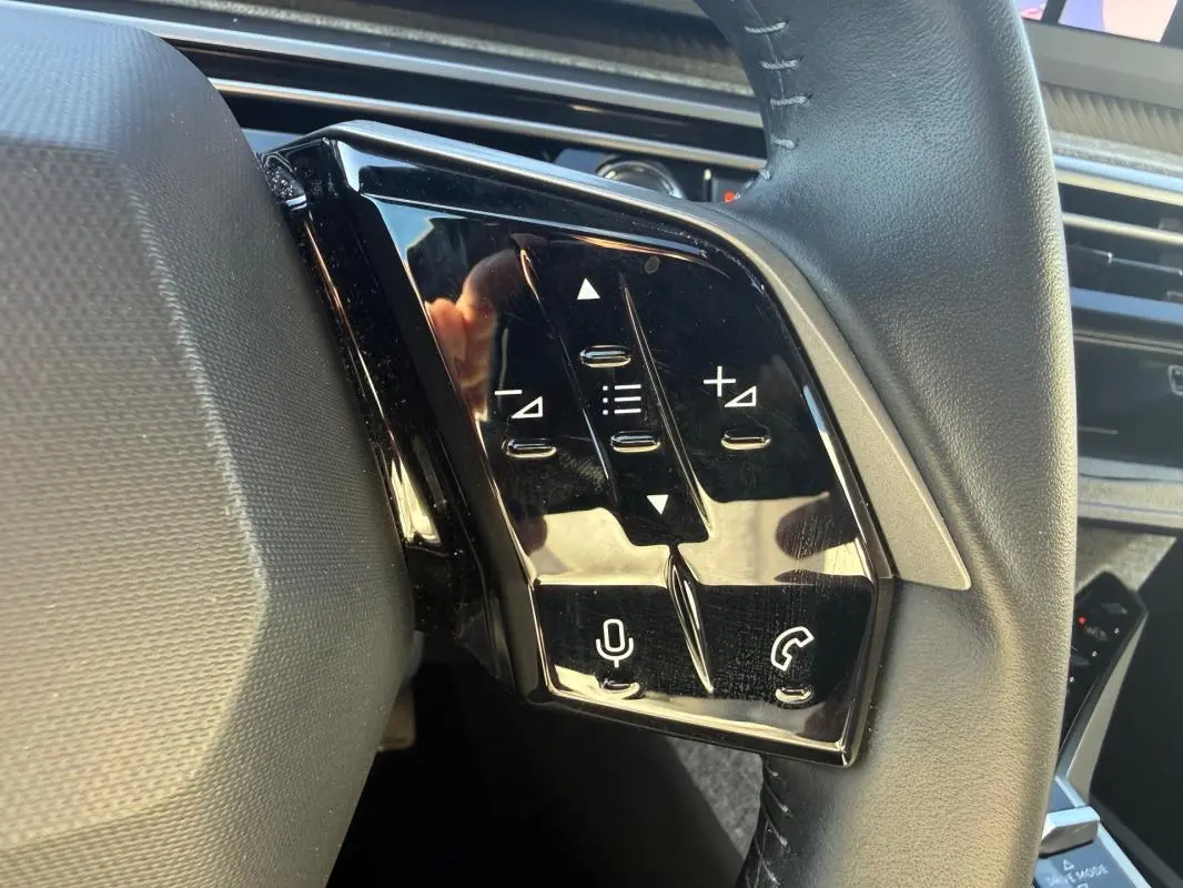 Gros plan sur les commandes tactiles noires à gauche du volant du Peugeot 3008 Hybrid gris, version 2025.