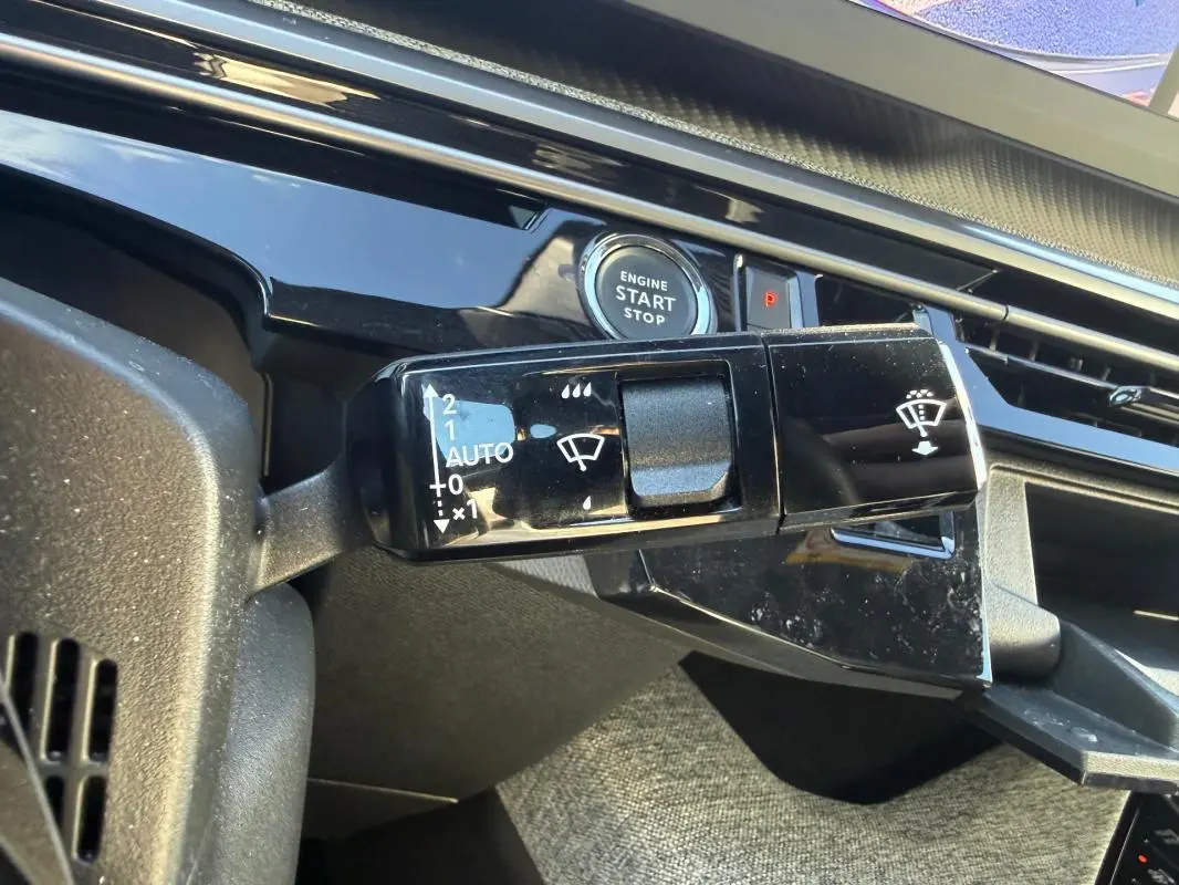 Gros plan sur la commande d’essuie-glace et bouton start/stop du tableau de bord gris du Peugeot 3008 Hybrid 145 Allure 2025.
