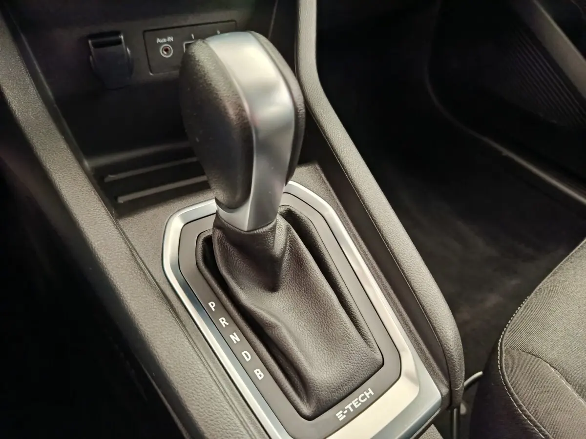Gros plan sur le levier de vitesses automatique noir et argenté de la Renault Clio Business E-TECH 140, intérieur sombre.