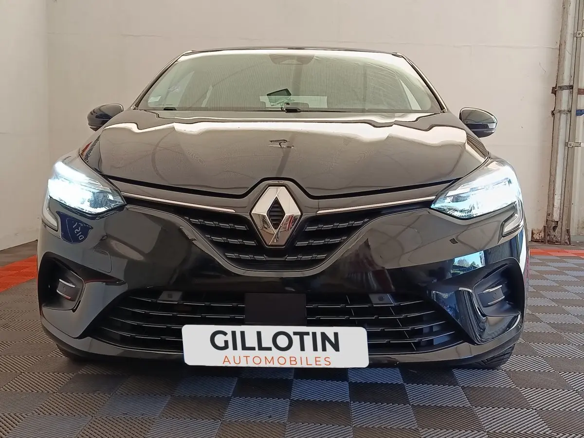 Vue frontale d'une Renault Clio Business E-TECH 140 noire avec phares LED allumés et calandre distinctive.