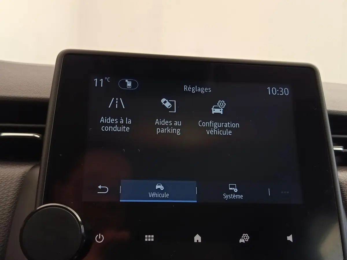 Écran tactile central de la Renault Clio Business E-TECH 140 affichant les réglages d’aides à la conduite et au parking.