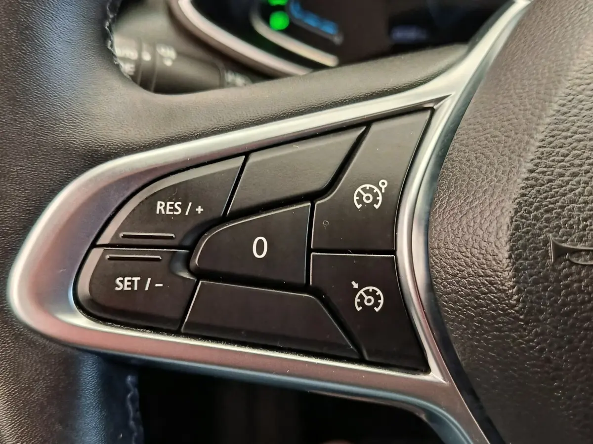 Gros plan sur les commandes de régulateur de vitesse au volant cuir noir de la Renault Clio Business E-TECH 140.