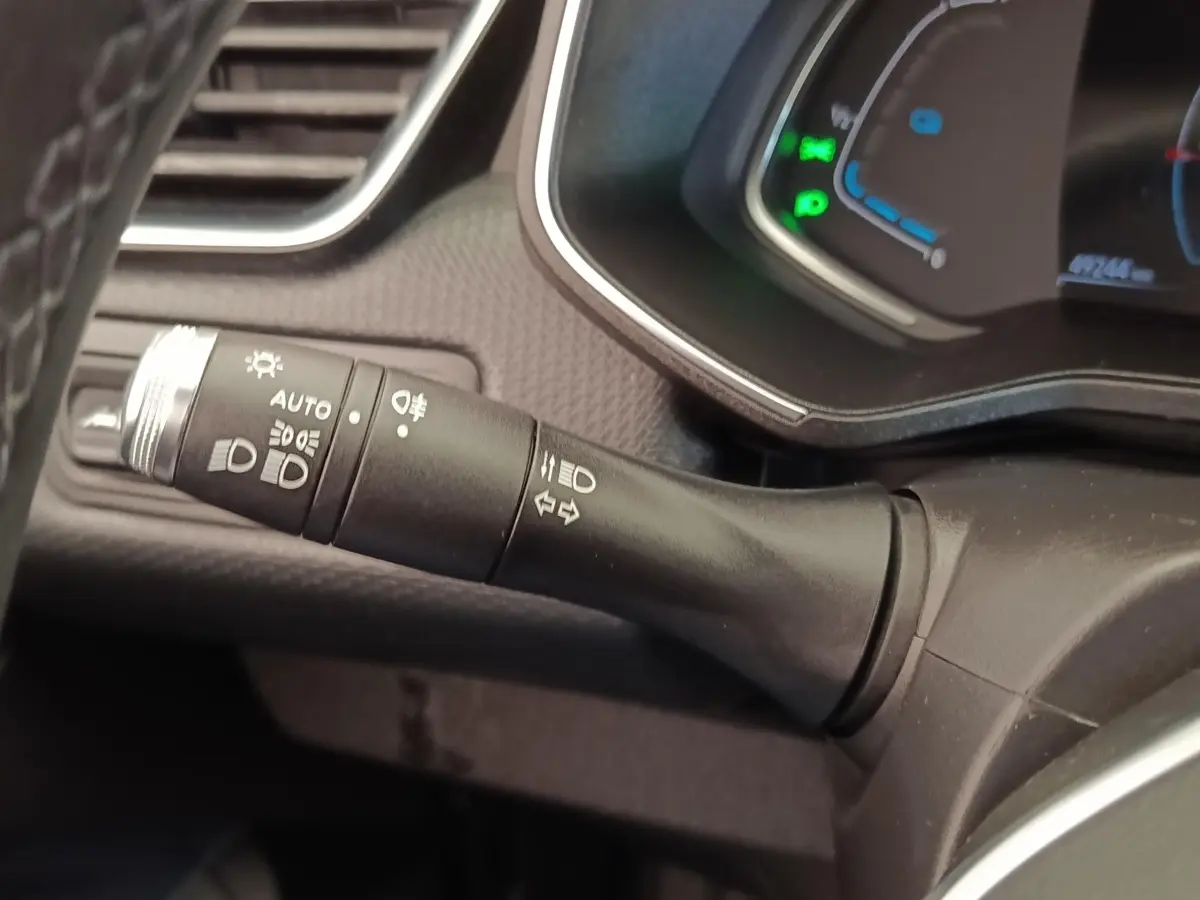 Gros plan sur la manette de commande des phares et clignotants dans l’habitacle d’une Renault Clio Business E-TECH blanche.