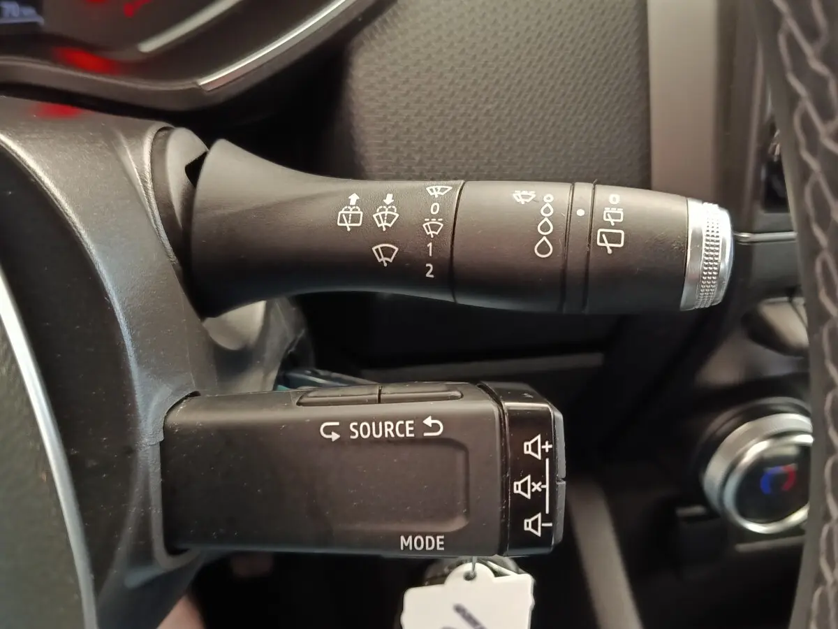 Gros plan sur les commandes au volant noir de la Renault Clio Business E-TECH 140, avec indications blanches et molette argentée.