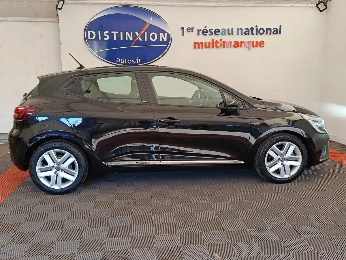 Profil droit d'une Renault Clio Business E-TECH 140 noire, avec jantes alliage et logo Distinxion en arrière-plan.