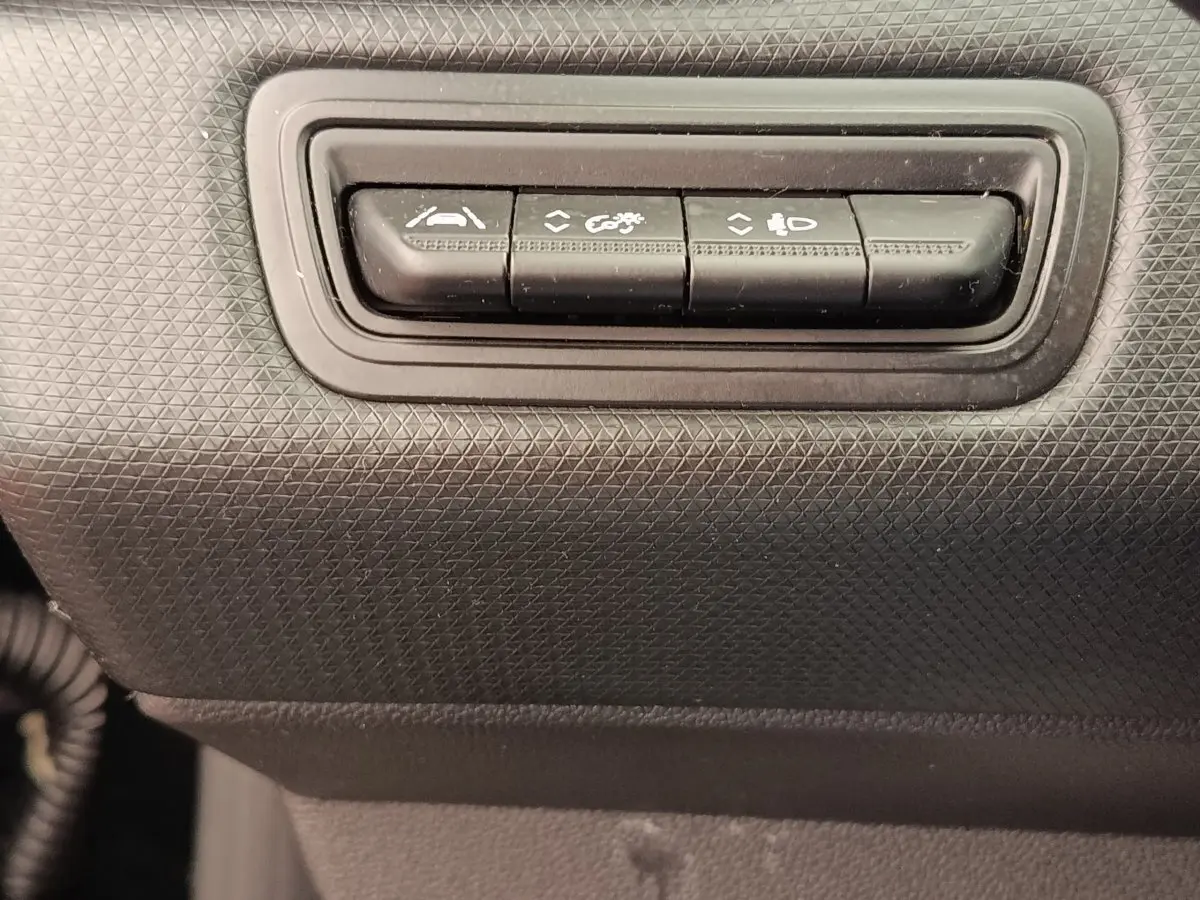 Gros plan sur les boutons de commande d'aide à la conduite dans l'habitacle noir d'une Renault Clio Business E-TECH 140.