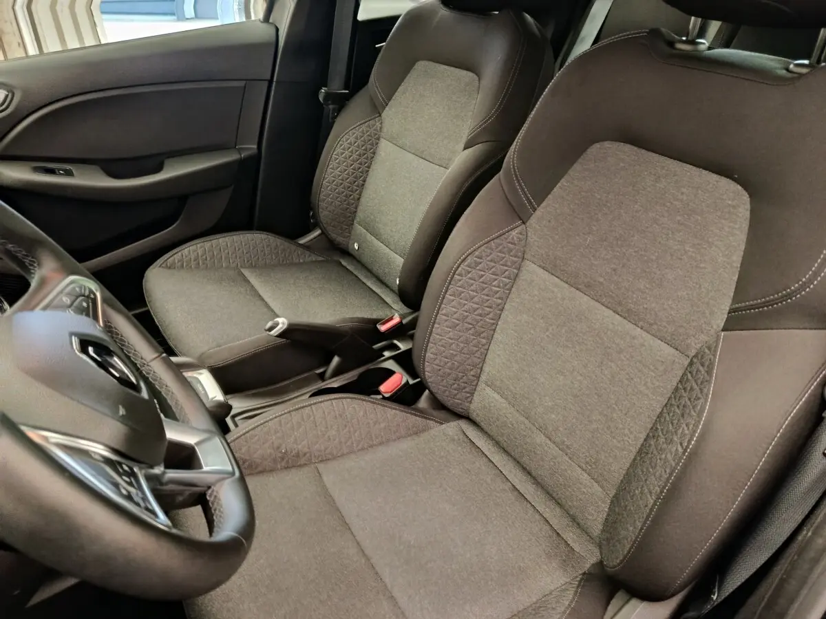 Vue intérieure rapprochée des sièges avant gris et noir de la Renault Clio Business E-TECH 140 avec volant cuir multifonctions.