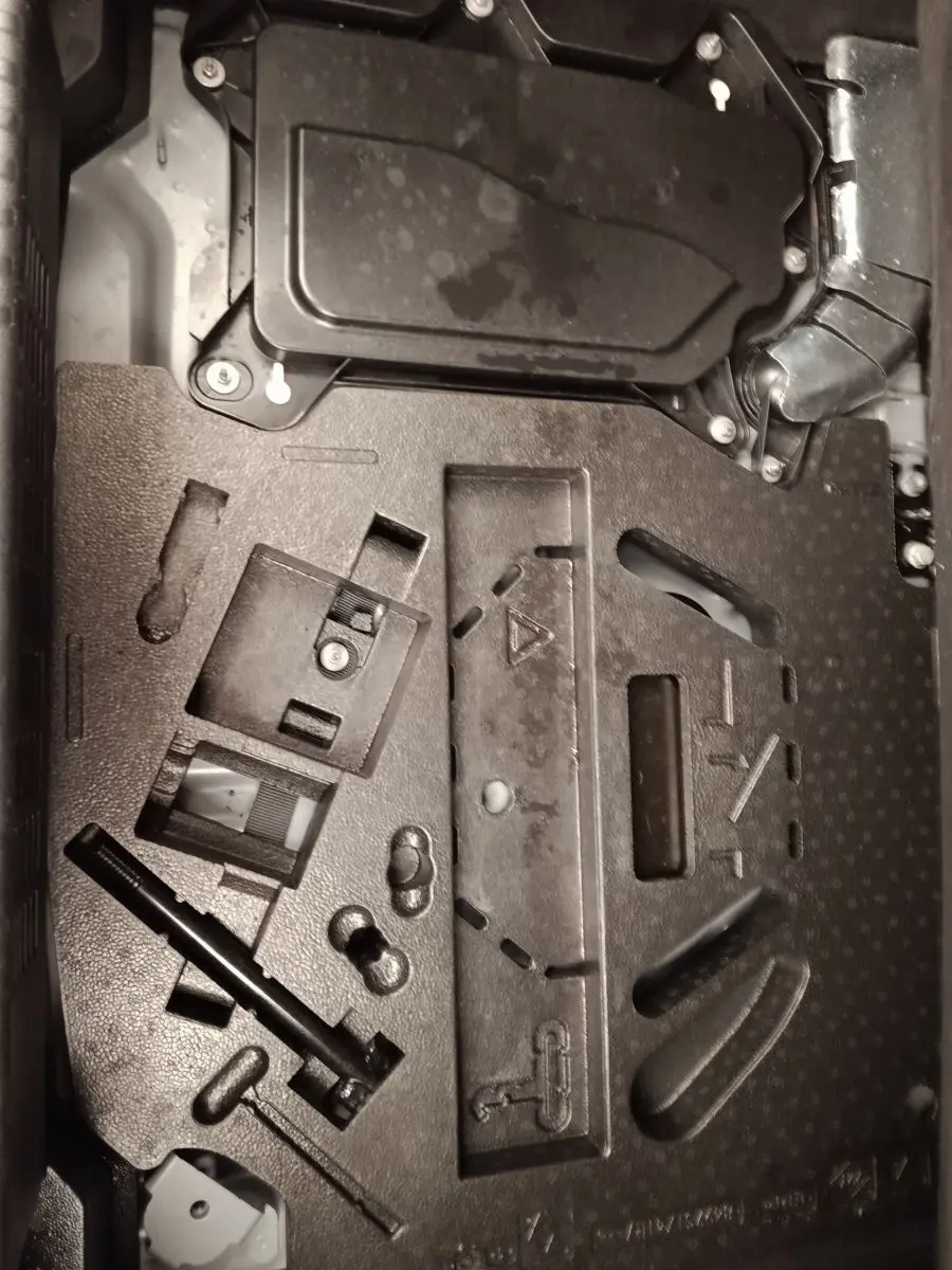 Vue rapprochée du compartiment de rangement sous le plancher de coffre de la Renault Clio Business E-TECH 140 blanche.