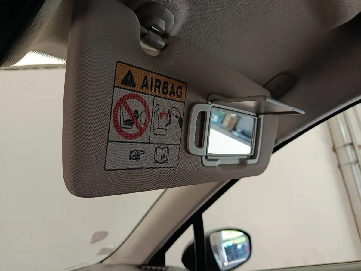 Miroir de courtoisie ouvert sur pare-soleil beige côté conducteur dans l'habitacle d'une Renault Clio blanche.