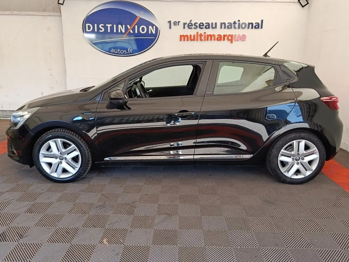 Profil côté gauche d'une Renault Clio Business E-TECH 140 noire, avec jantes alliage et vitres teintées, en intérieur showroom.