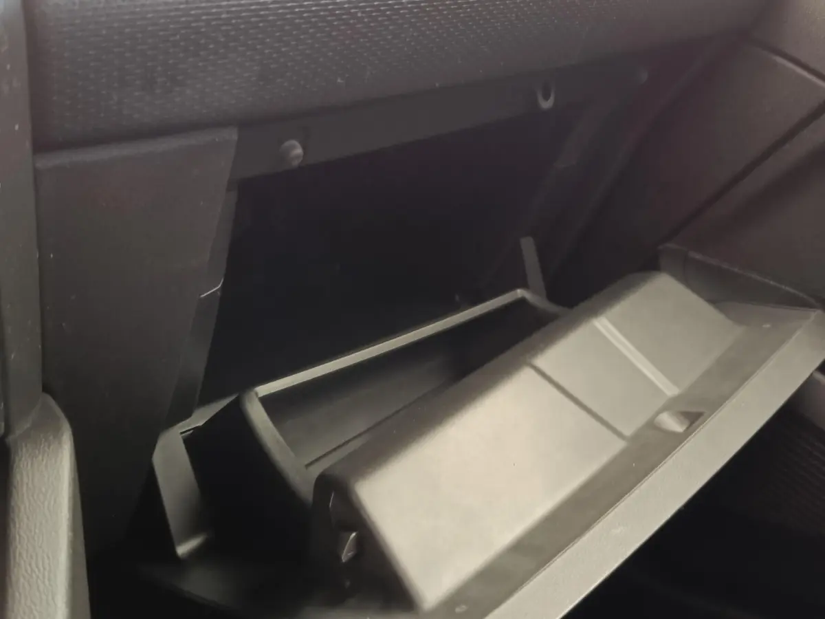 Gant de boîte à gants ouvert côté passager dans l'habitacle sombre d'une Renault Clio Business E-TECH 140 blanche.