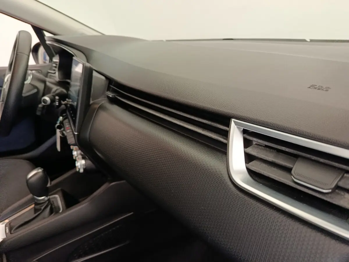 Vue intérieure côté passager du tableau de bord noir texturé de la Renault Clio Business E-TECH 140 avec aérateurs chromés.