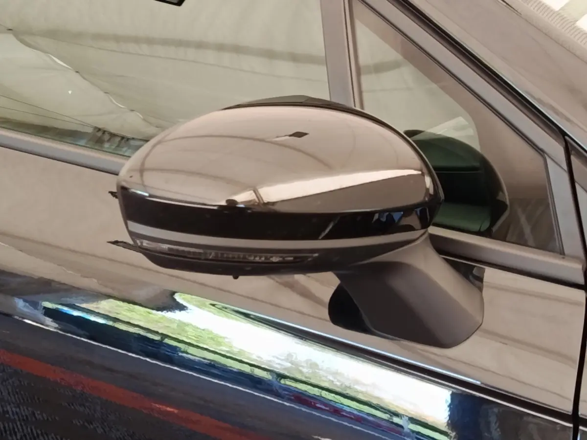 Gros plan sur le rétroviseur droit noir brillant d’une Renault Clio Business E-TECH 140 blanche, reflet visible sur la carrosserie.