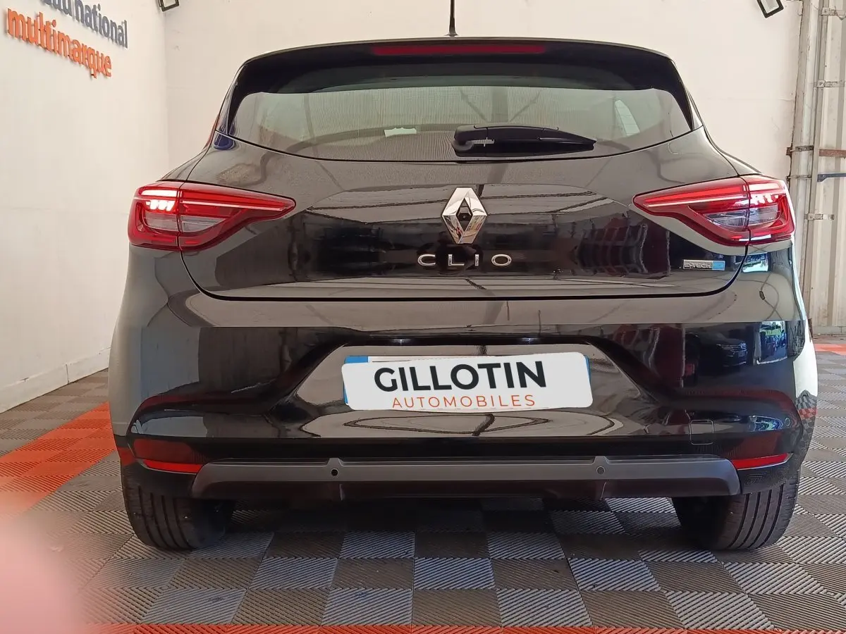 Vue arrière d'une Renault Clio noire avec feux LED allumés et logo Renault bien visible.