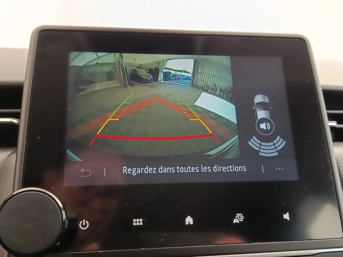 Écran tactile intérieur montrant la caméra de recul et l’aide au stationnement de la Renault Clio Business E-TECH blanche.