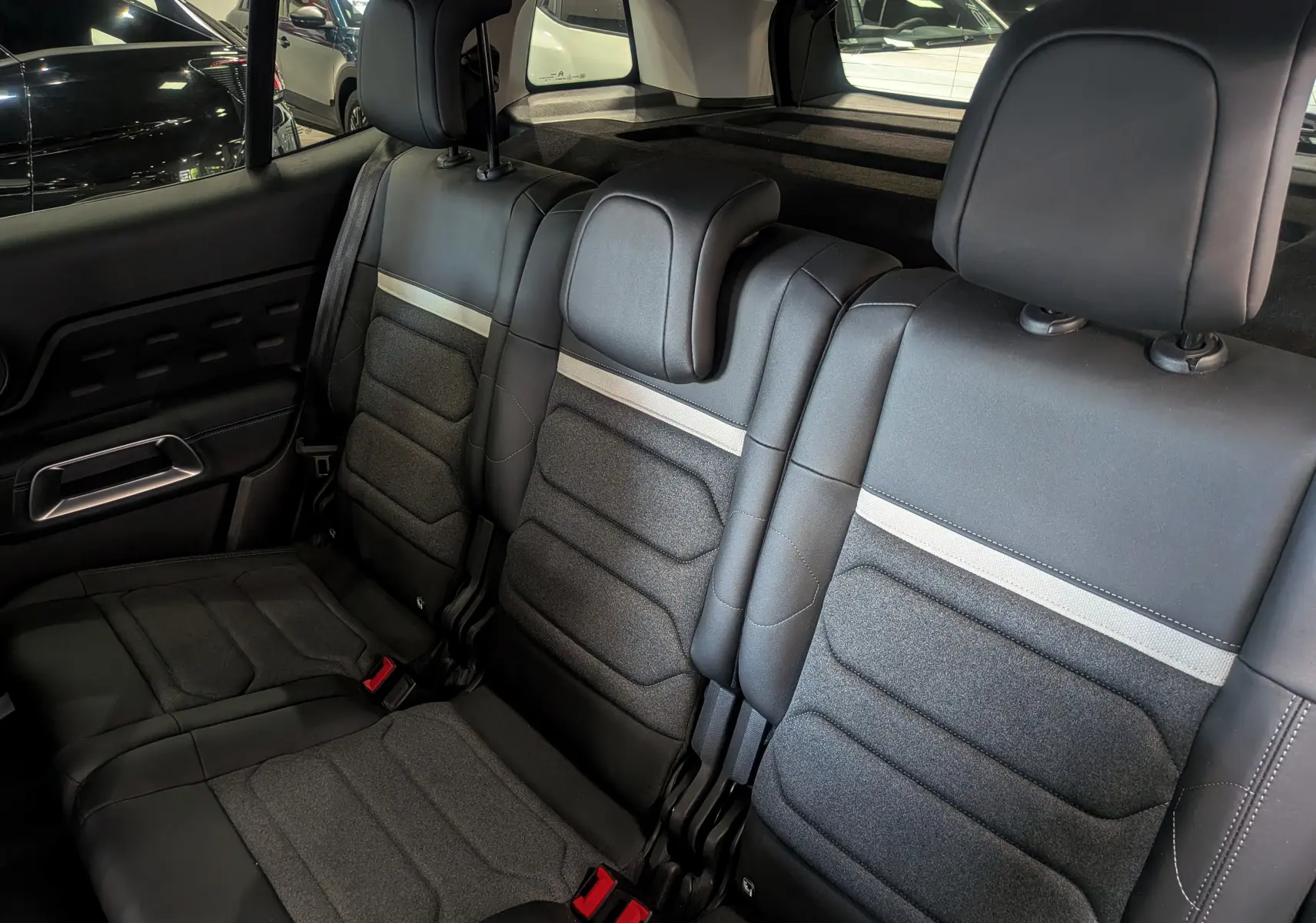 Vue intérieure arrière du Citroën C5 Aircross hybride 2025, sièges noirs avec bande grise et appuie-têtes réglables.