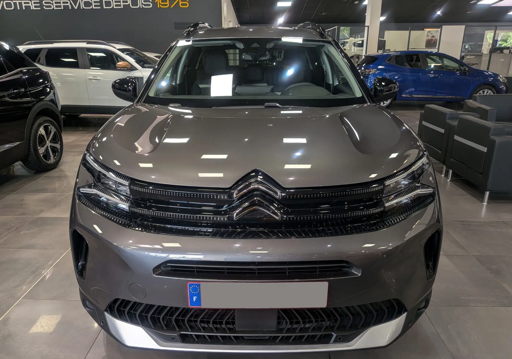 Vue frontale d'un Citroën C5 Aircross Hybride gris Platinium, soulignant la calandre et les phares LED au showroom.