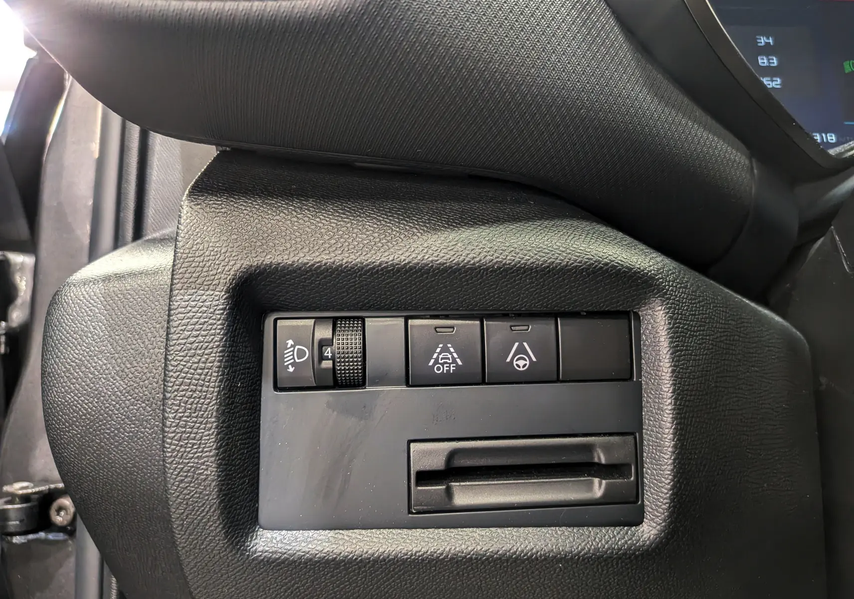 Gros plan sur les commandes de réglage d'éclairage et d'assistance à la conduite du tableau de bord noir du Citroën C5 Aircross hybride.