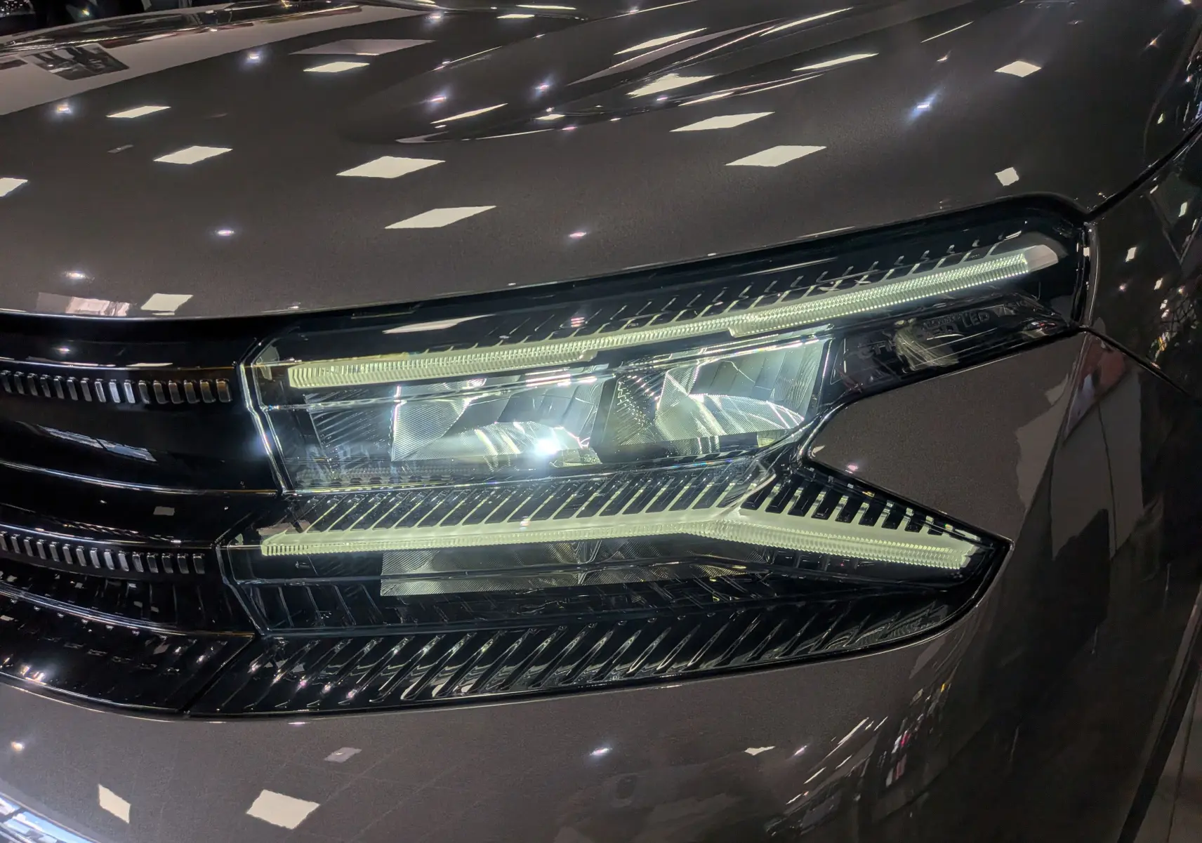 Gros plan sur le phare avant droit du Citroën C5 Aircross Hybride gris Platinium, mettant en valeur les LED distinctives.