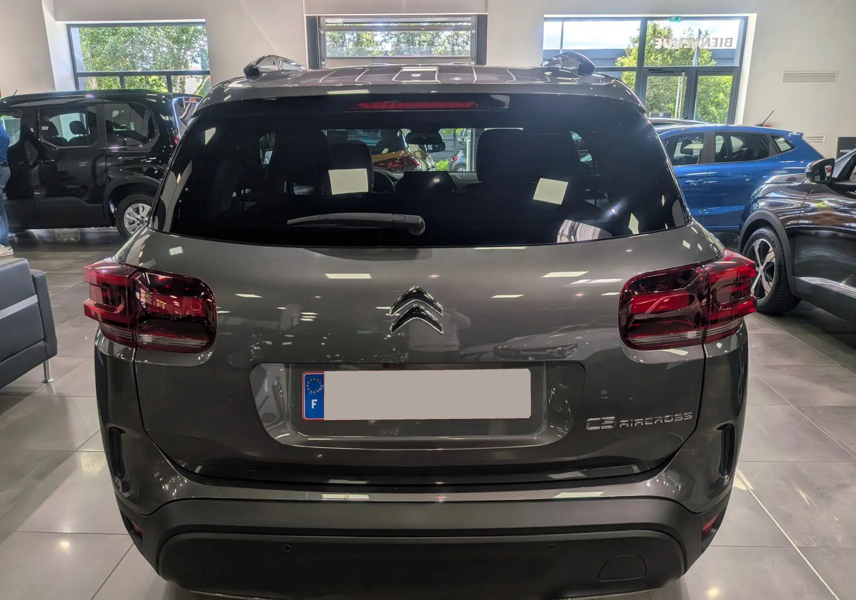 Vue arrière d'un Citroën C5 Aircross gris Platinium en showroom, avec feux arrière rouges et logo Citroën visible.