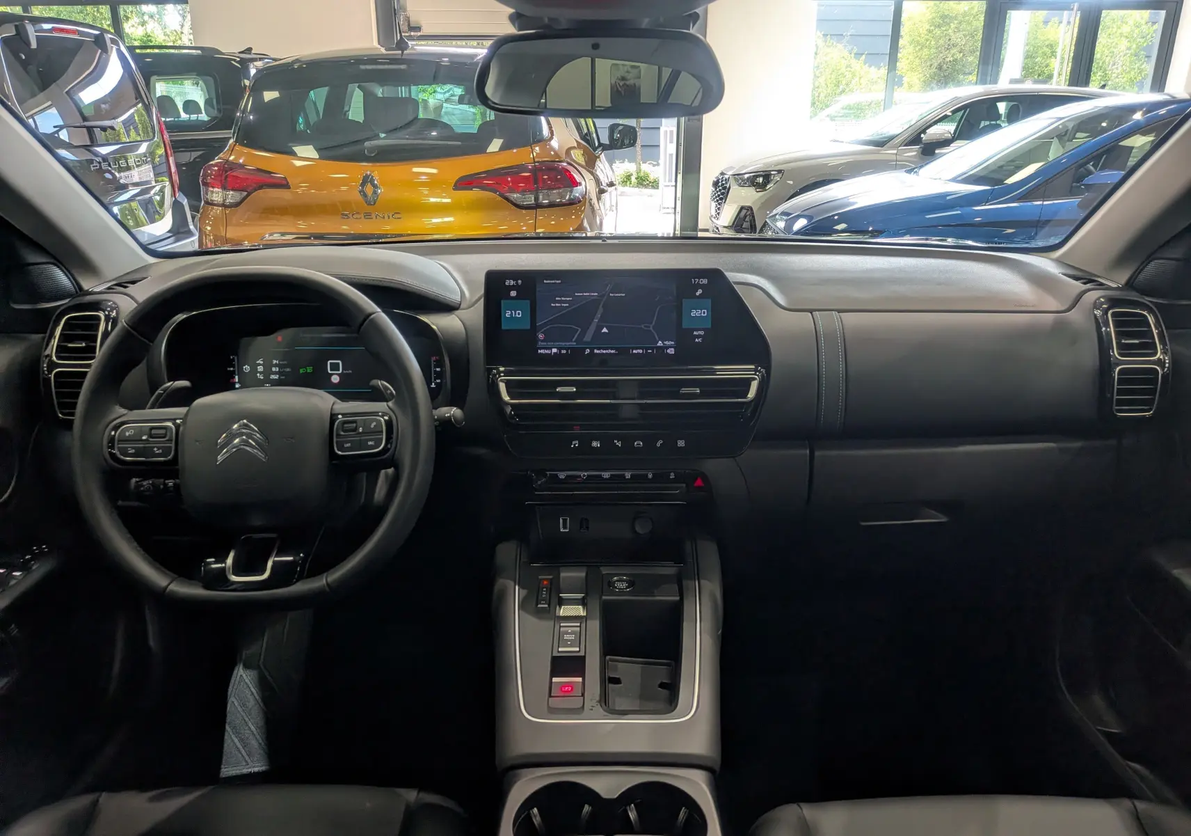 Vue intérieure frontale du tableau de bord noir du Citroën C5 Aircross hybride 2025 avec écran tactile central et volant multifonction.