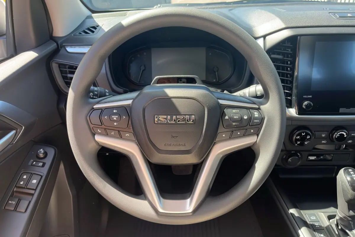 Vue intérieure centrée sur le volant multifonctions gris de l'Isuzu D-MAX 2026 avec tableau de bord et écran tactile.
