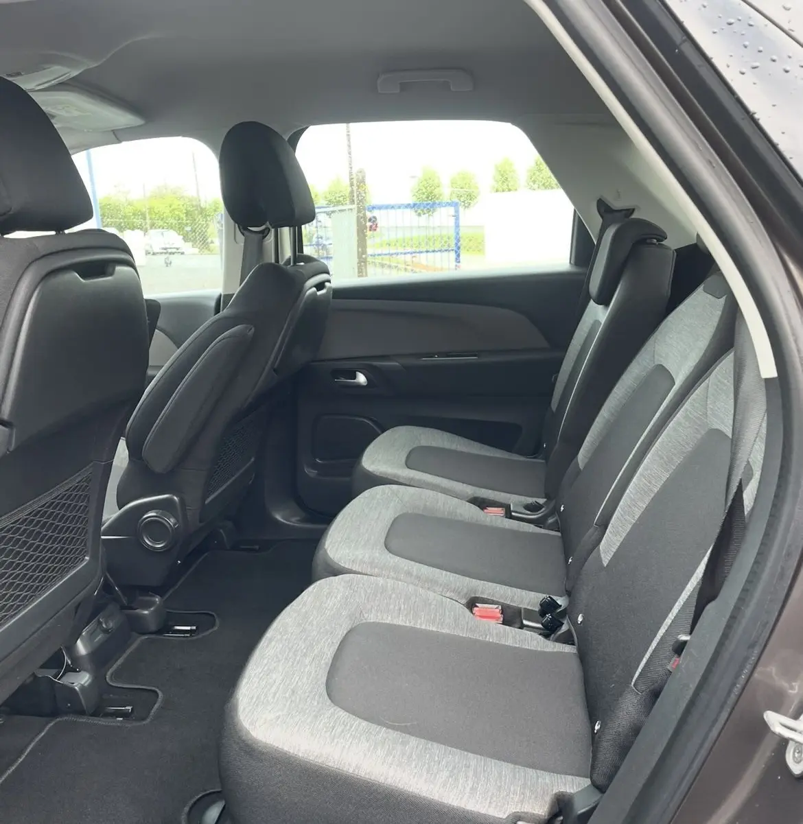 Détail de la console côté gauche d'une Citroën C4 Picasso marron, montrant les aérateurs et commandes d'éclairage.