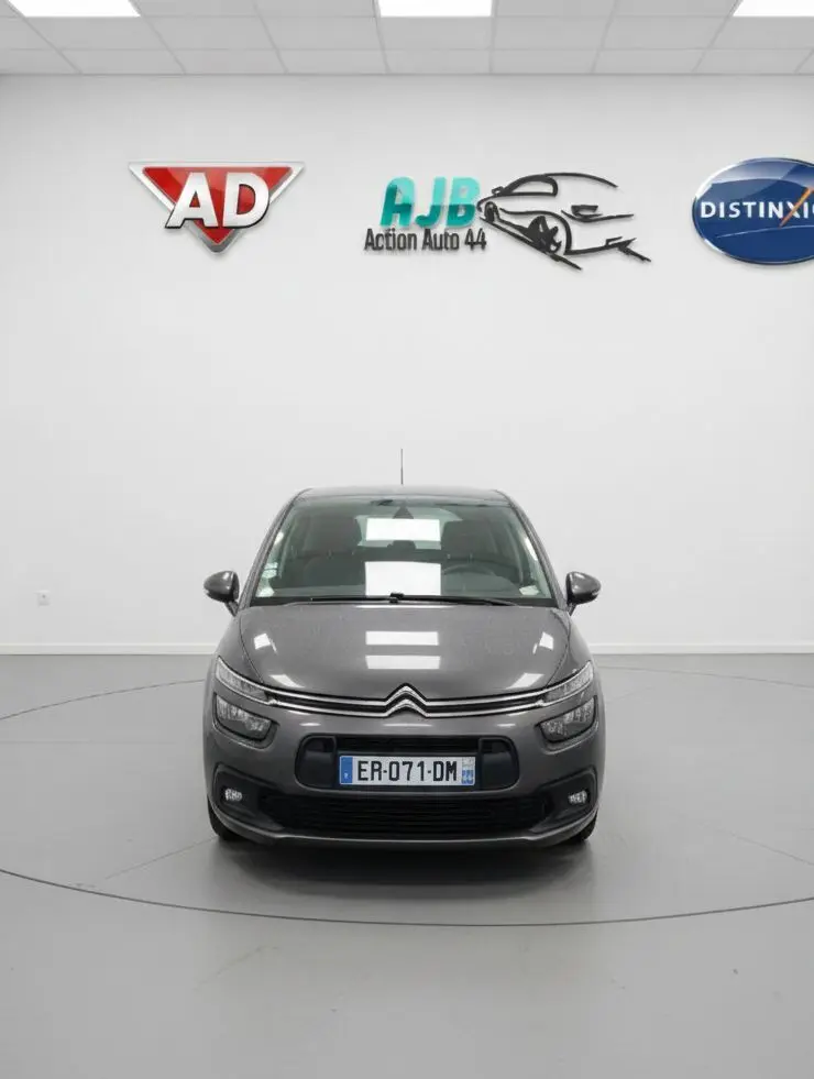 Citroën C4 Picasso marron vue de face sous la pluie, avec feux de jour LED et calandre distinctive.