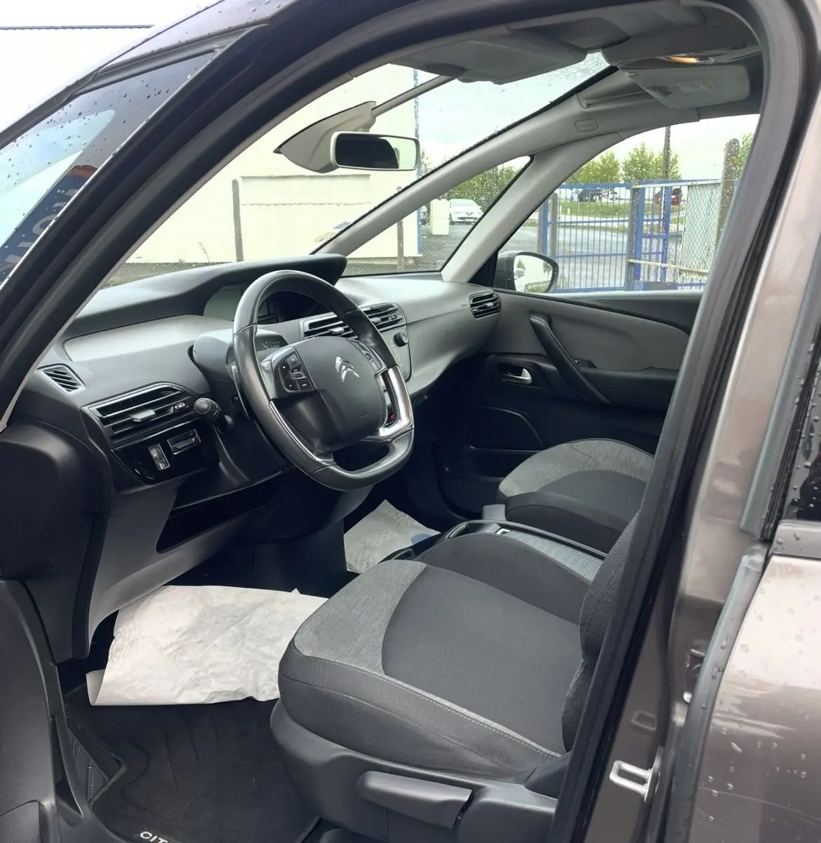 Gros plan sur la roue arrière gauche et la portière marron d'une Citroën C4 Picasso avec jante alu au design moderne.