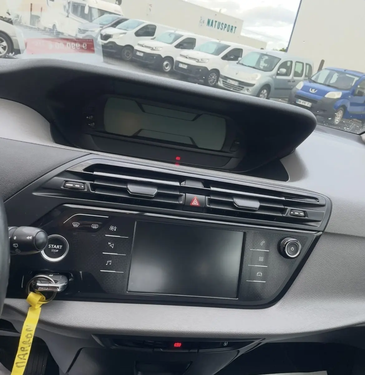 Gros plan sur la roue avant gauche et l'aile d'une Citroën C4 Picasso marron sous la pluie avec jante alu bicolore.