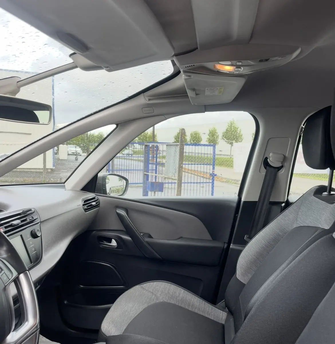 Vue intérieure centrée sur le volant cuir multifonction d'une Citroën C4 Picasso 2017, tableau de bord et écran tactile visibles.