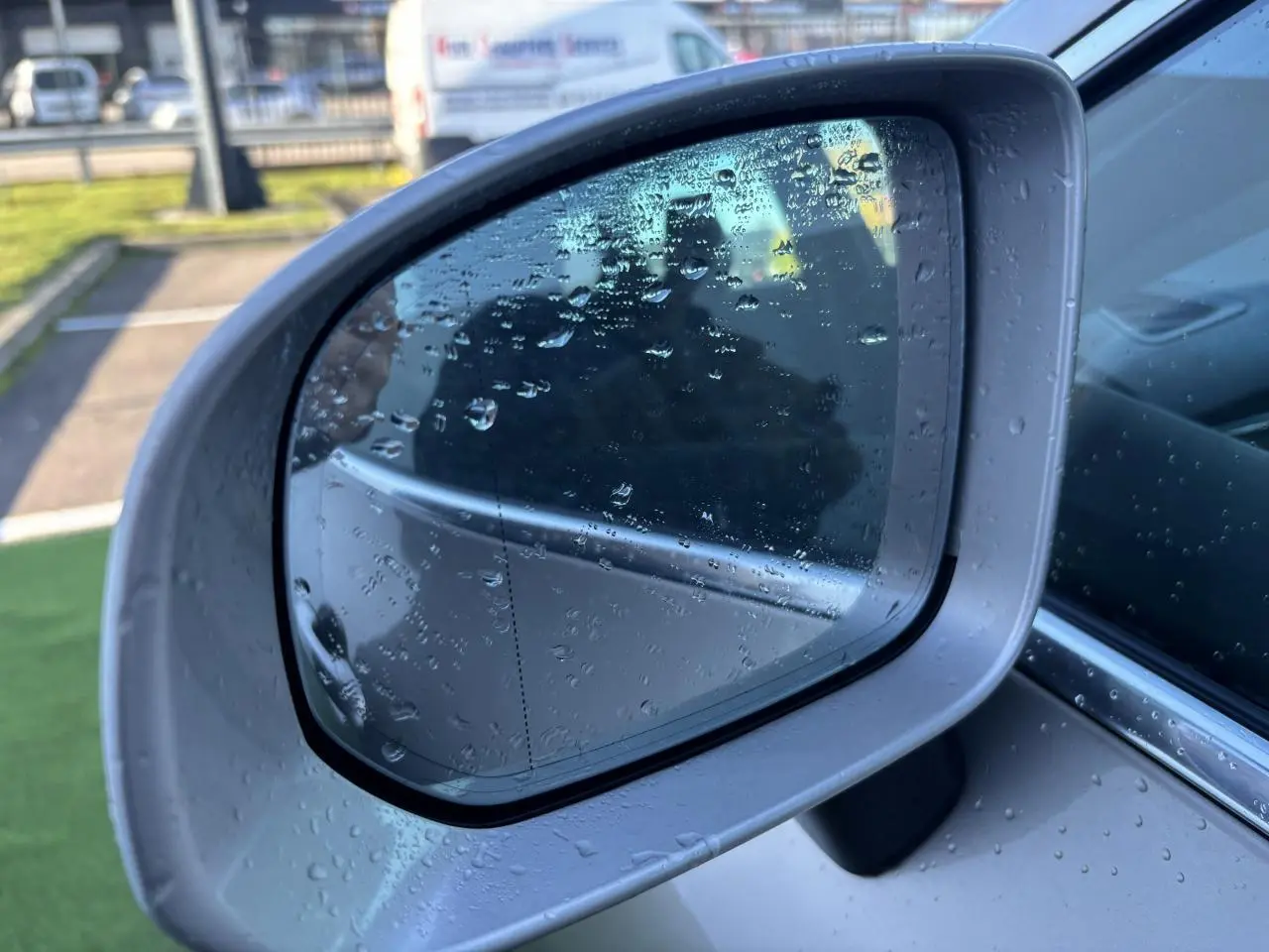 Rétroviseur extérieur côté gauche argent du Volvo XC60 2024 avec gouttes d'eau sur la surface.
