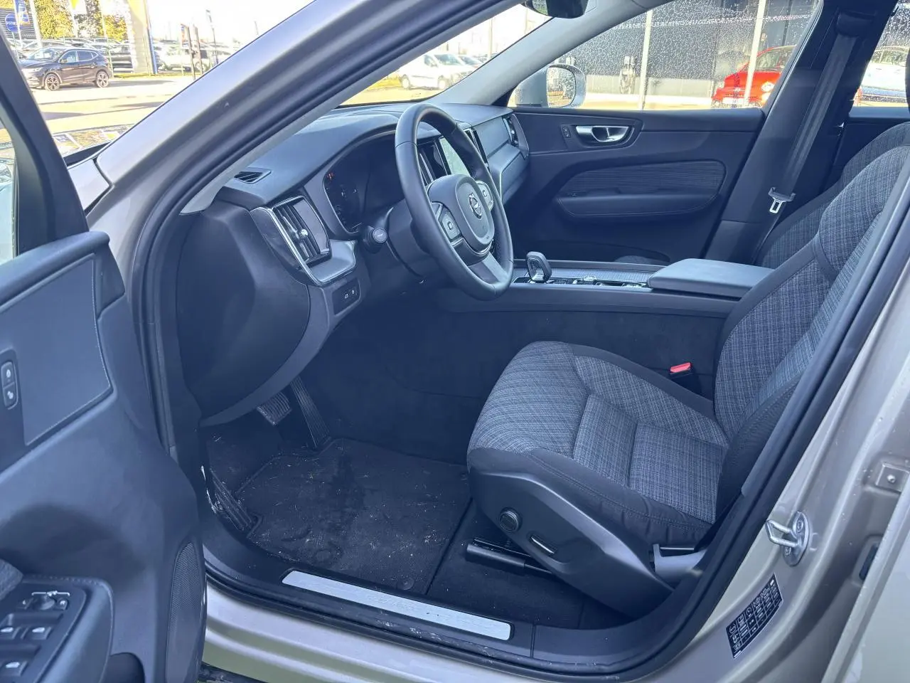 Intérieur côté conducteur du Volvo XC60 argent crépuscule, volant 3 branches et sièges tissu gris à motifs.