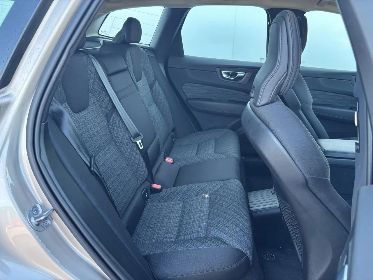 Vue intérieure côté gauche sur les sièges arrière en tissu gris à motifs du Volvo XC60 2024 argent crépuscule métal.