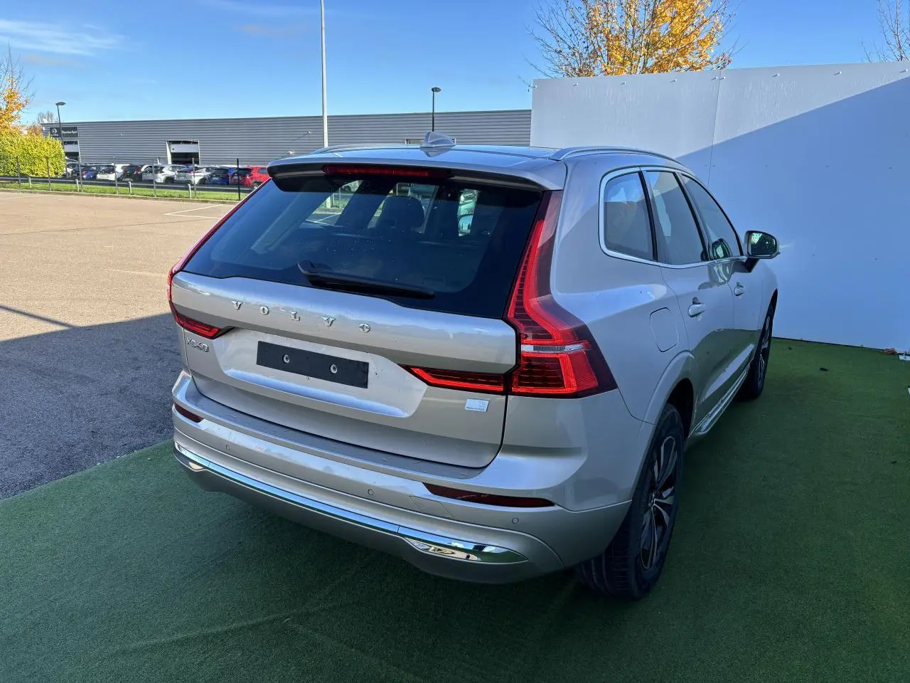 Vue 3/4 arrière droite d'un Volvo XC60 argent crépuscule métal avec feux arrière LED et jantes alliage noires.