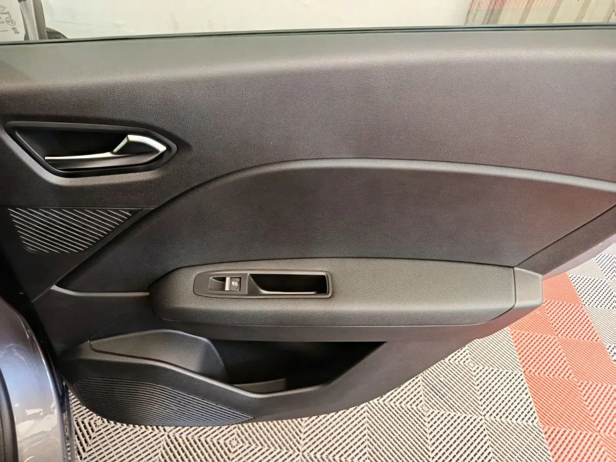 Vue côté gauche de la porte intérieure noire du Renault Captur 2025 avec poignée et commande de vitre électrique.