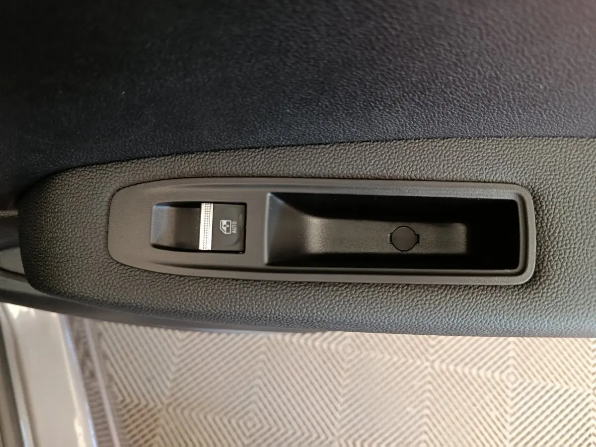 Gros plan sur le bouton de commande de lève-vitre côté conducteur du Renault Captur gris foncé 2025.