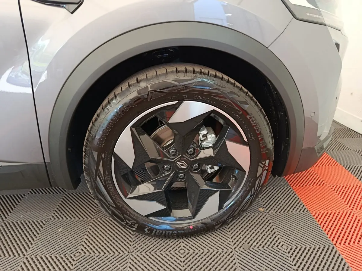 Gros plan sur la roue avant droite d'un Renault Captur gris foncé avec jante noire et argent au design géométrique.