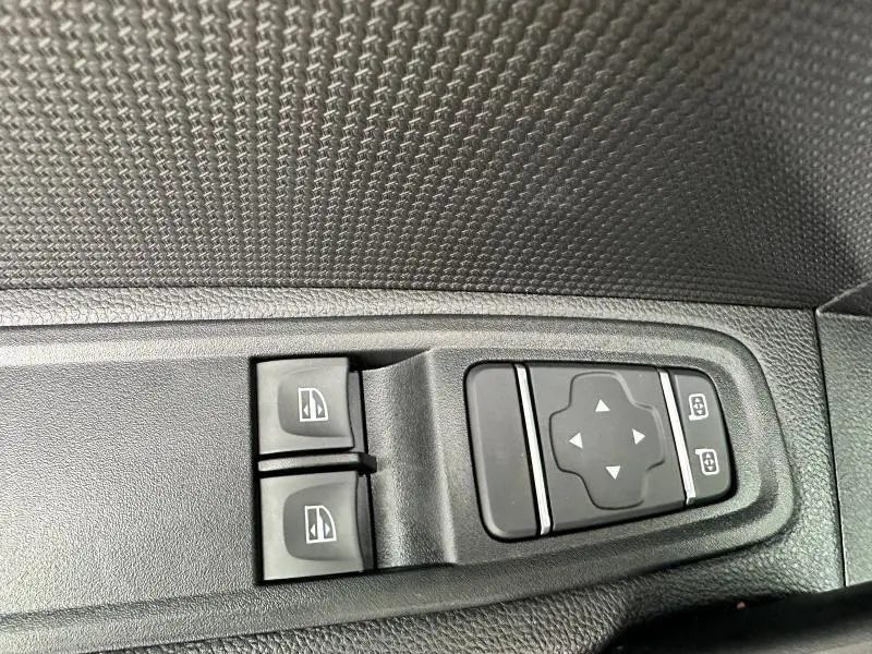 Commandes électriques des vitres et réglages des rétroviseurs sur la porte côté gauche d'un Nissan Townstar gris 2024.