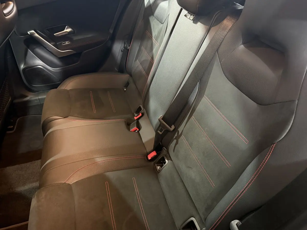Vue intérieure côté arrière droit des sièges en cuir noir avec surpiqûres rouges dans une Mercedes Classe A A 200 AMG Line 2021.